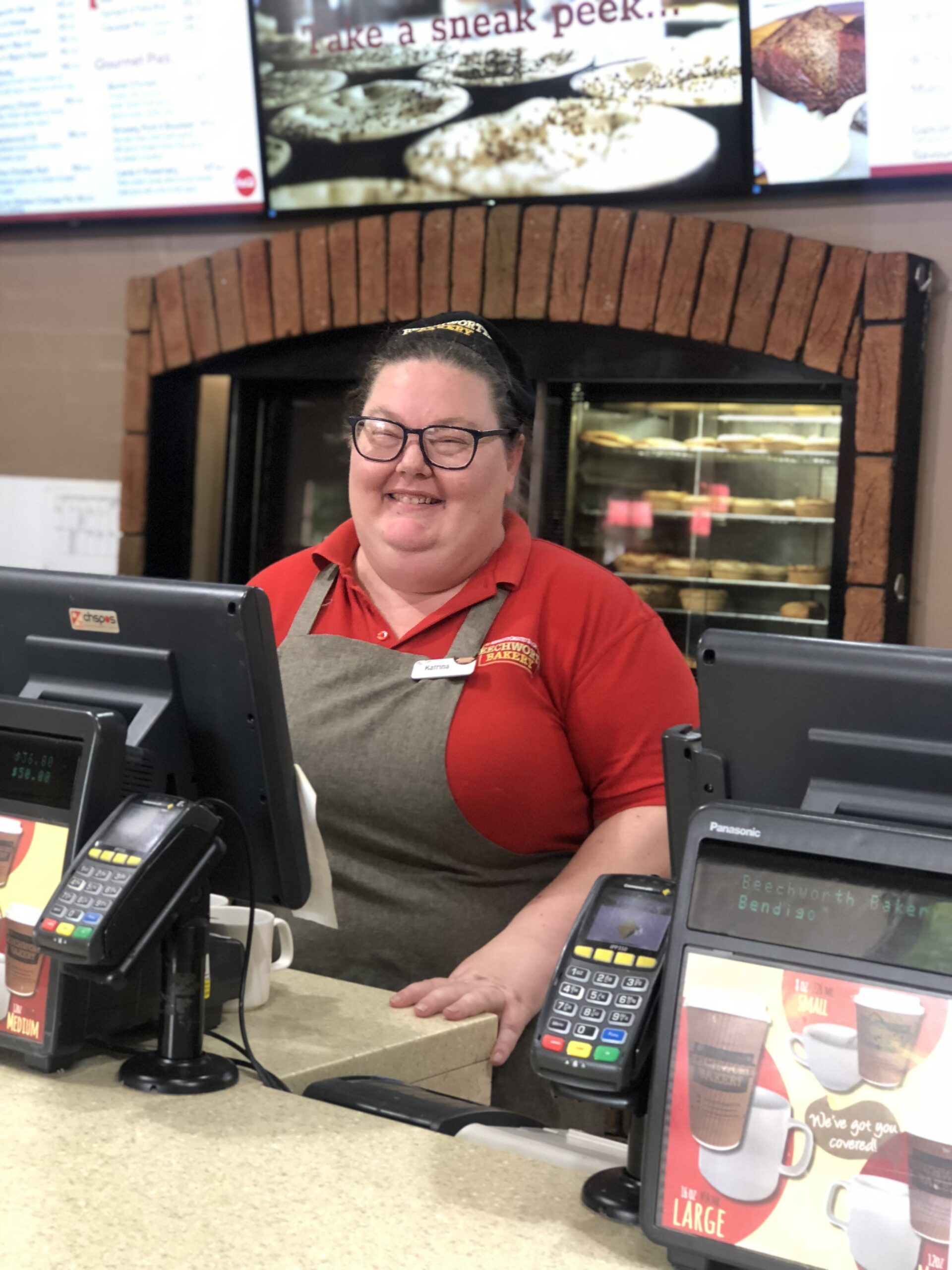 Katrina dressed in her beechworth bakery uniform standing behind the cash register
