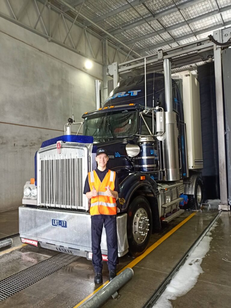 Tyson wearing a high-visibility vest standing in front of a truck giving thumbs-up